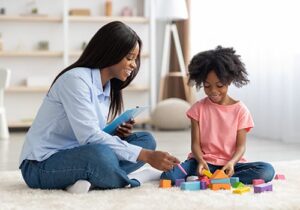Health professional works with child, by utilizing blocks, during autism spectrum disorder therapy in MA