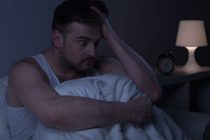 Person sitting up in bed at night, thinking about the myths about anxiety