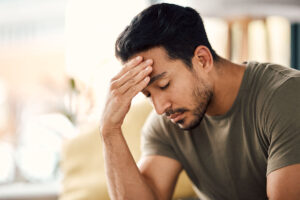 man with head in hands considers how anxiety can look different in men